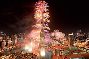 A nighttime cityscape with a prominent skyscraper and fireworks.