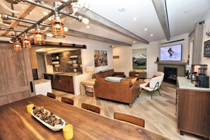 Ein modernes Wohnzimmer mit Kamin, Fernseher und Essbereich mit Holztisch und Stühlen.