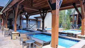 A covered outdoor swimming pool area with lounge chairs and a hot tub.