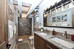 Ein modernes Badezimmer mit Dusche, einem großen Spiegel und einer Arbeitsplatte aus Granit.