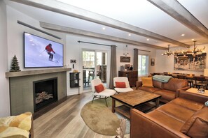 A modern living room with a fireplace, leather sofas, a television, and a dining area.