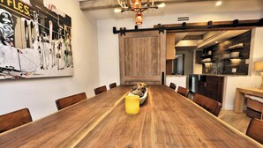 A wooden dining table with chairs, a yellow vase, and a wall-mounted ski-themed artwork.