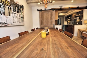 Una mesa de comedor de madera con sillas, un jarrón amarillo y una obra de arte con temática de esquí colgada en la pared.