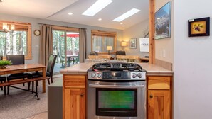 Une cuisine moderne dotée d’un îlot central, d’un four encastré et d’un coin repas avec une table et des chaises en bois.