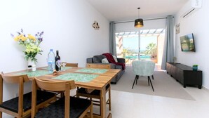 A modern living room with a dining area, a sofa, a TV, and a view of the outdoors. - Harmony of Sea View & Nature,1BR (Polis Chrysochous)