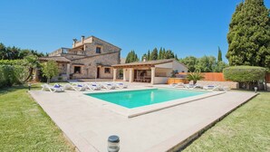 Une maison à deux étages avec une piscine, une pergola et une pelouse bien entretenue.