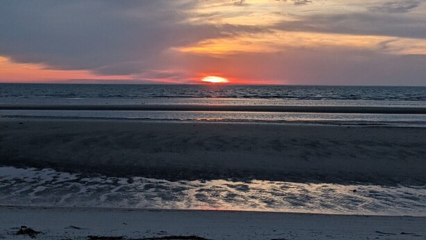 A beach scene with the sun setting over the horizon. - Cozy White Cottage by the Bay (Lower Township)