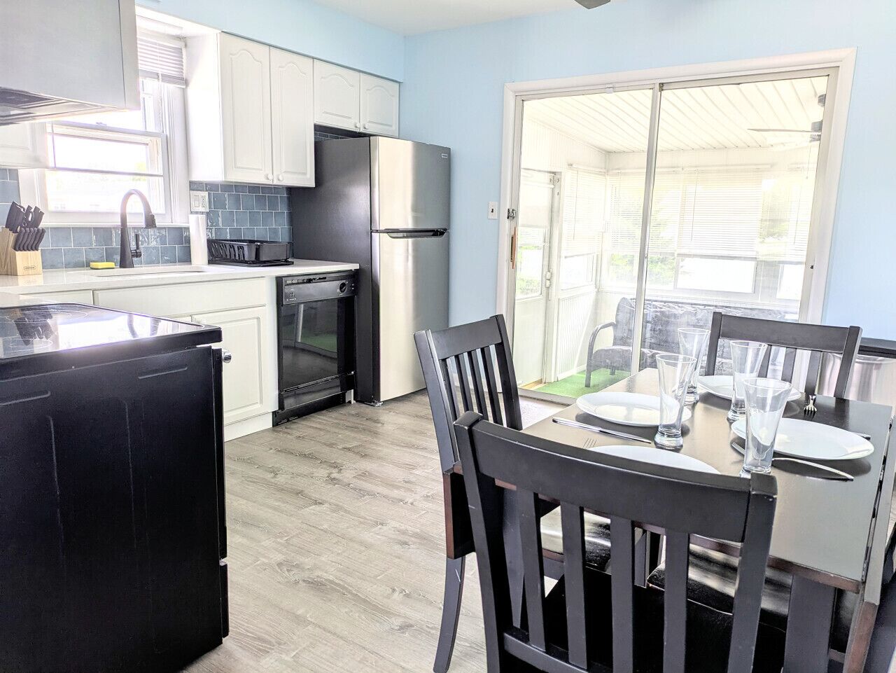 A compact kitchen with white cabinets, a black refrigerator, and a dining table set for four.