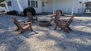 A house with a covered porch, a fire pit, and four Adirondack chairs. - Cozy White Cottage by the Bay (Lower Township)