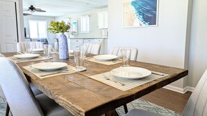 A dining area with a wooden table set for four, surrounded by upholstered chairs. - Summer Breezes, Bay Views (Lower Township)