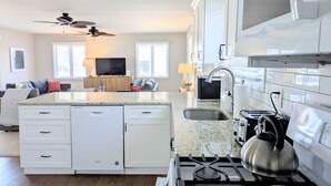 A modern kitchen with white cabinetry, a built-in stove, and a large island with a sink. - Summer Breezes, Bay Views (Lower Township)