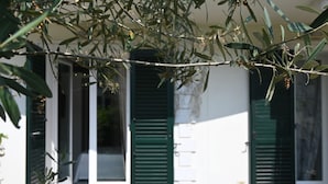 A building with green shutters, a white facade, and a door leading to a covered entrance. - P071 – Porto Recanati, Three-Room Apartment with Garden and Wi-Fi (Porto Recanati)