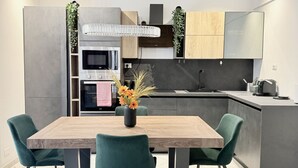 A modern kitchen with a dining area, featuring a wooden table, teal chairs, and a vase with flowers. - P071 – Porto Recanati, Three-Room Apartment with Garden and Wi-Fi (Porto Recanati)