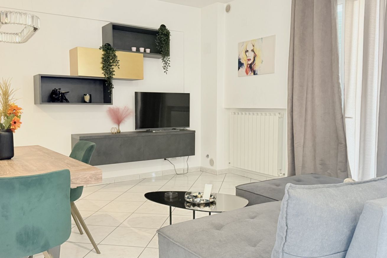 Un soggiorno moderno con televisione, divano, tavolo da pranzo e piante decorative.