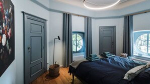 A bedroom with a bed, a floor lamp, a window with curtains, and a painting on the wall. - Paviljoen De Notelaer (Bornem)