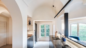A modern kitchen with a central island, a large window, and a view of greenery. - Paviljoen De Notelaer (Bornem)