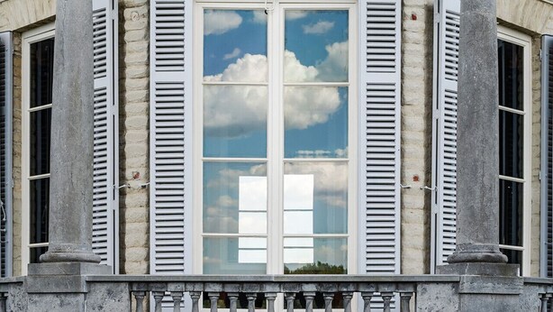 A building with a stone facade, a balcony with balustrades, and a window with shutters. - Paviljoen De Notelaer (Bornem)
