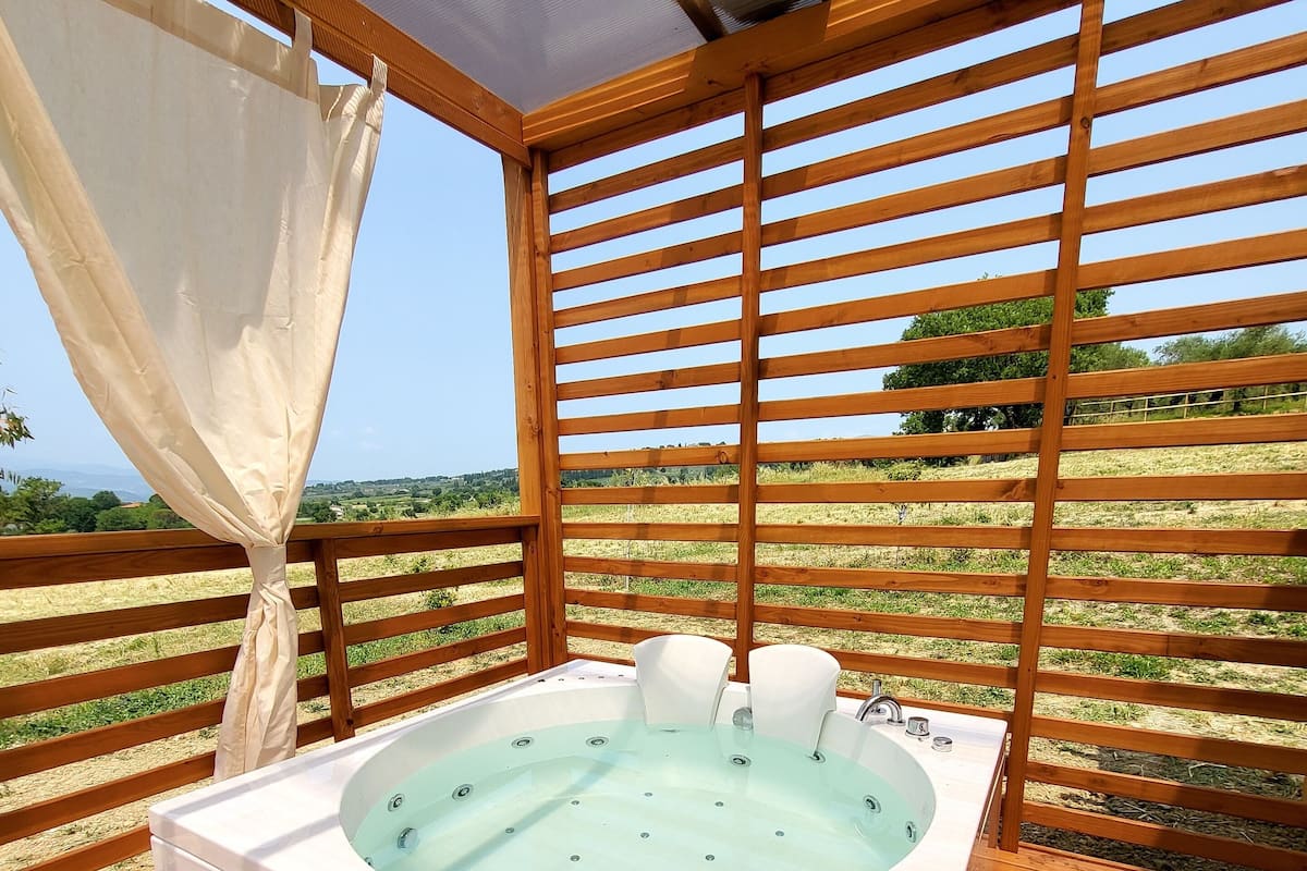 Un bain à remous sur une terrasse en bois, avec vue sur un vignoble.