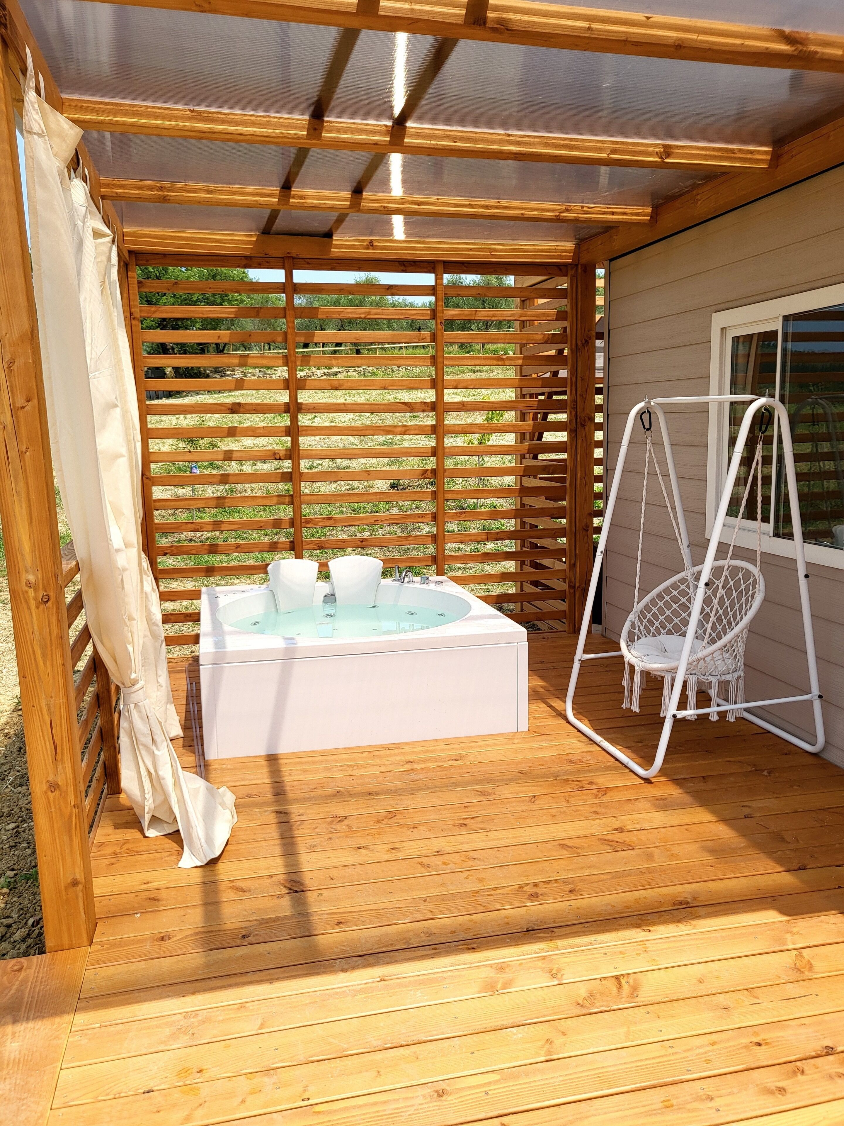 Una terraza de madera con un jacuzzi y una silla colgante.