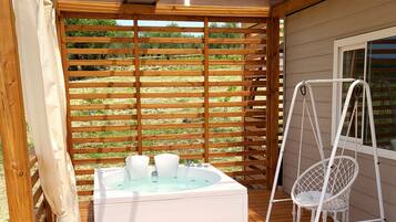 Una terraza de madera con un jacuzzi y una silla colgante.