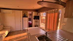 A compact kitchenette with a sink, a small refrigerator, and a television.