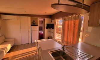 A compact kitchenette with a sink, a small refrigerator, and a television.