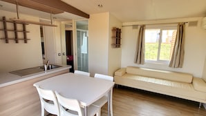 A modern kitchen with a dining area, a sofa, and a window with curtains.
