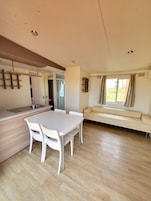 Una cocina moderna con comedor, sofá y ventana con cortinas.