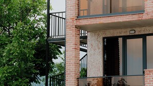 A multi-story building with a brick facade, large windows, and a balcony with a glass railing. - Villa Ikalto (Telavi)