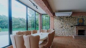 A dining area with a large table and chairs, a stone wall, and a fireplace. - Villa Ikalto (Telavi)