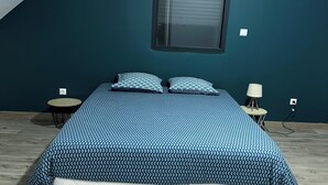 A bedroom with a bed, two pillows, a window, and a small table. - Spacious new house with 4 bedrooms - Close to the Loire castles (Joué-lès-Tours)