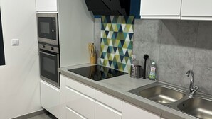 A modern kitchen with white cabinets, a double sink, a microwave, and a stove. - Spacious new house with 4 bedrooms - Close to the Loire castles (Joué-lès-Tours)