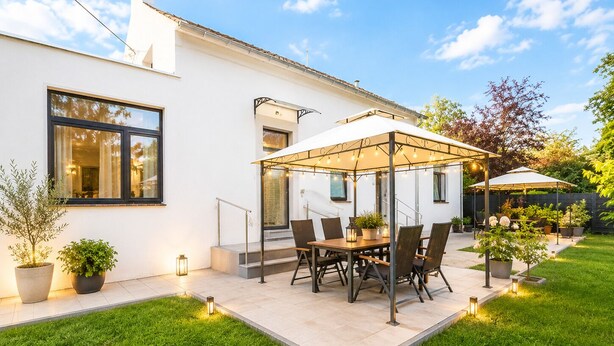 A patio with a table and chairs, surrounded by potted plants and a white building. - Airport Messe Apartments (Düsseldorf)