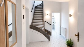 A modern staircase with a wooden finish, white walls, and a tiled floor. - Airport Messe Apartments (Düsseldorf)