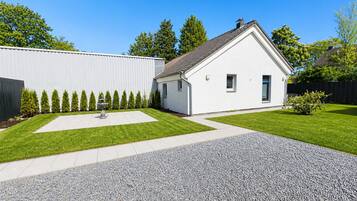 Uma casa moderna com fachada branca, calçada pavimentada e gramado bem cuidado.
