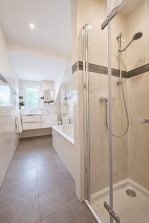 Une salle de bain moderne avec une douche à parois de verre, un meuble-lavabo blanc avec un miroir et une baignoire.