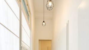 A hallway with a radiator, a black rug, and a door leading to another room. - Airport Messe Apartments (Düsseldorf)