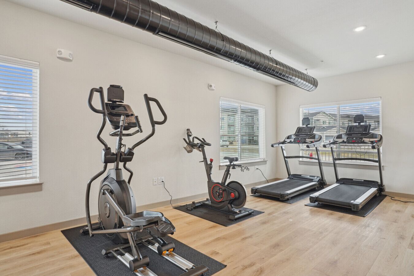 Une salle de sport équipée de vélos d’appartement, d’un appareil elliptique et de tapis de course.
