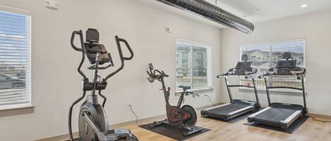 Une salle de sport équipée de vélos d’appartement, d’un appareil elliptique et de tapis de course.