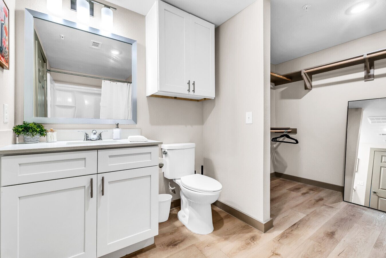 A modern bathroom with a white vanity, a toilet, and a large mirror.