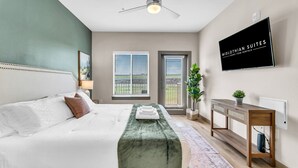 Une chambre à coucher moderne avec un lit, une table de chevet, une télévision et une vue sur l’extérieur.