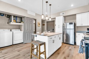 A modern kitchen with a central island, stainless steel appliances, and wooden flooring. - Pool, Gym, New Build, Mins to DT Waco & BU | TZ2 (Lacy Lakeview)