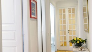 A hallway with wooden flooring, white doors, and a small table with a vase of flowers.