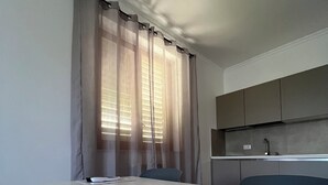 Une pièce minimaliste comprenant un lit, un bureau et une fenêtre ornée de rideaux légers.