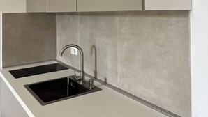 Une cuisine dotée d’un plan de travail blanc, de deux éviers noirs et d’un robinet en acier inoxydable.