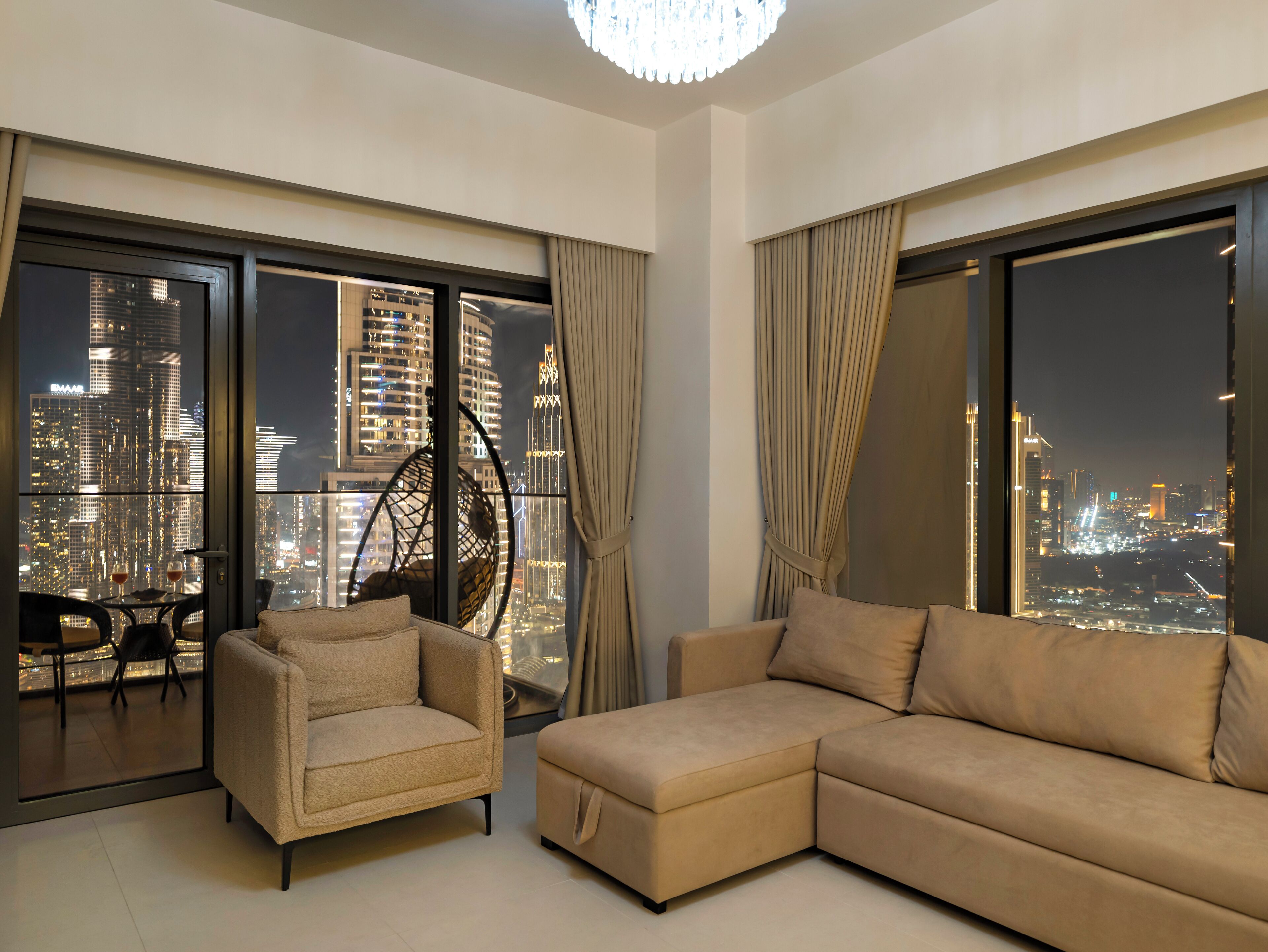 A modern living room with a large window offering a city view, a sofa, a chair, and a hanging chair.