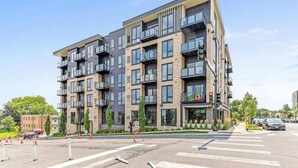 Un immeuble résidentiel moderne à plusieurs étages, doté de balcons, de grandes fenêtres et d’un passage pour piétons à l’avant.