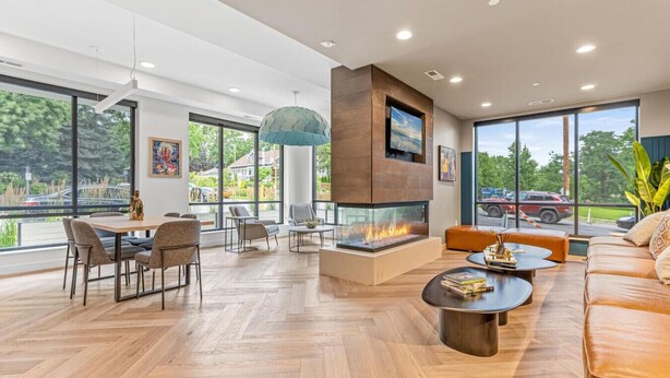 Un salon spacieux doté d’une cheminée, de grandes fenêtres et d’un parquet en bois disposé en point de Hongrie.