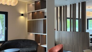 A modern interior with a black sofa, red chairs, and a wooden table. - LaCorniche (Contrexéville)