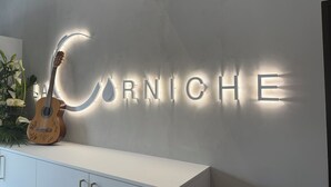 A wall with illuminated letters spelling "CARNICHE" and a guitar on a white cabinet.